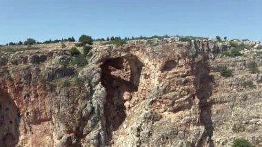 Turistler dikilip Keshet Mağarası 'na bakıyorlar. İsrail' in Shlomi kenti yakınlarında geniş manzaralı sığ bir mağaranın kalıntılarını kaplayan antik doğal kireçtaşı kemeri.