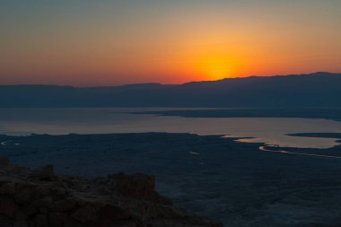 Ürdün dağlarının ve Ölü Deniz 'in üzerinden şafak sökerken. İsrail 'deki Massada Kalesi' nin harabelerinin bölgesinden görüş..