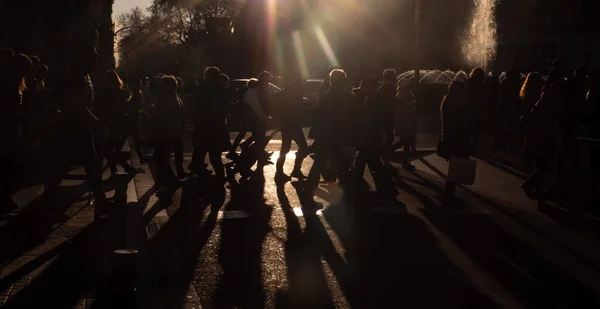 Crowd of anonymous people walking on sunset in the city streets silhouettes