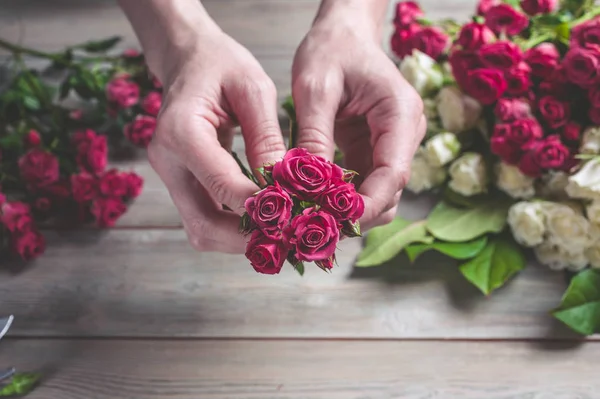 Florist at work. Female hands collect a wedding bouquet of roses. People in the process of work