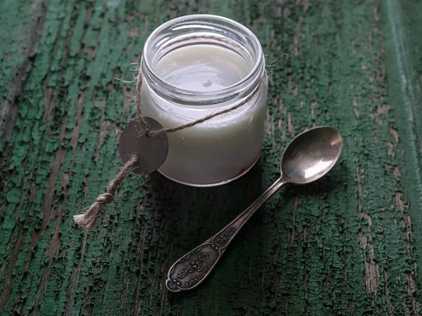 Homemade yogurt in a jar and a dessert spoon on a rustic background