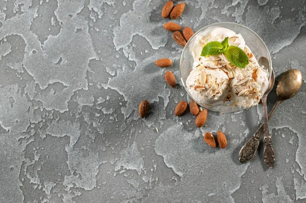 Vanilla ice cream with almonds on a gray concrete background. Top view