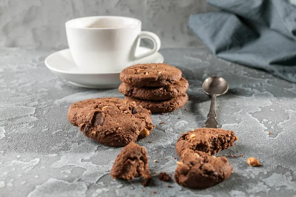 Chocolate biscuits and a cup of coffee on a gray concrete background.