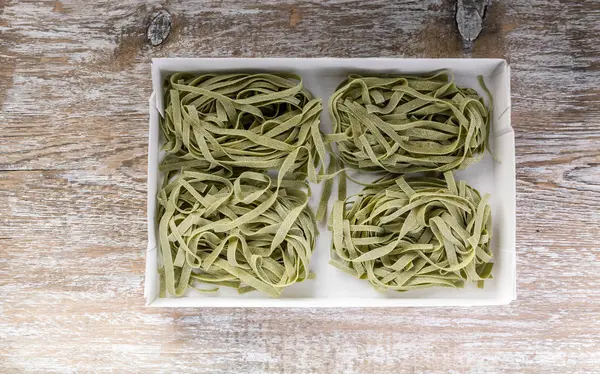 Raw pasta with pesto in a box on a wooden table. Top view