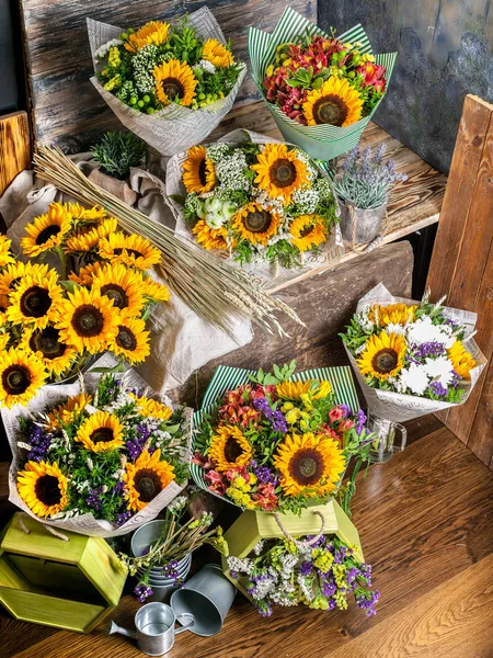 Workplace florist. Beautiful bouquets with sunflowers on a wooden table. vertical shot