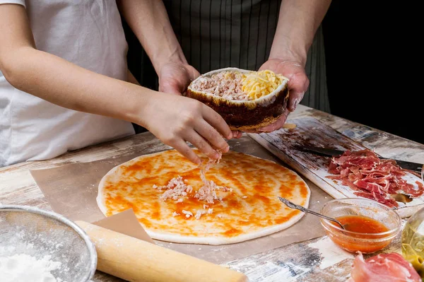 Moms and daughters hands cooking homemade pizza together. Ingredients and pizza making equipment on the background of the table. Food concept Cooking with mom