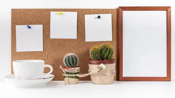 Workplace Mockup. Banner. Three white stickers, empty vertical frame, white cup, two cactus on a white background.