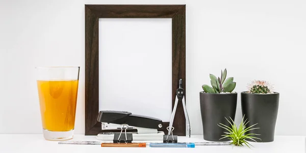 Banner Mock Up dark photo frame, two succulents, a glass of orange juice and stationery on a light background. Stationery set.