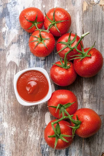 Vertical food banner tomatoes on a branch and tomato sauce or ketchup on a rustic background. Vertical shot