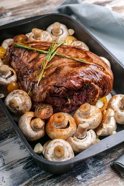 Marinated lamb with mushrooms, spices and herbs in a cast-iron mold on a wooden background. Halal meat and food. Close-up