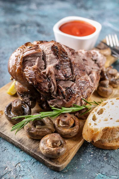 Close-up grilled ram leg with mushrooms, vegetables, spices on a cutting board. Halal meat and food