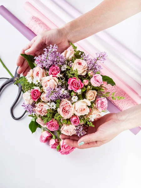 Small business concept. Work process of florist. Female hands making wedding bouquet on a white background.