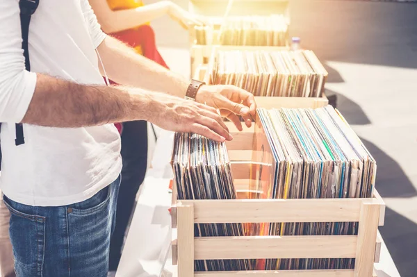 Man browsing vinyl album on sale. Beautiful male hands in the frame.