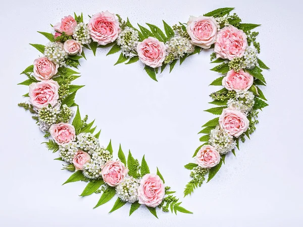 Wedding frame of flowers in heart-shaped: rose, hawthorn flowers, rowan leaves on a white background. Floral pattern. Copy space for text