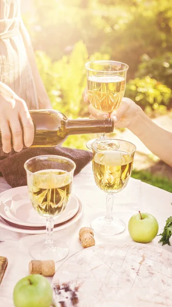 Woman pouring white wine. Dinner concept with wine in the fresh air. Fish and salads with vegetables and herbs. Mediterranean Kitchen. Vertical shot