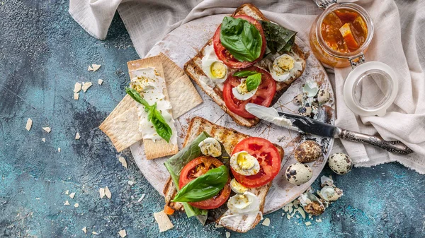 Food banner italian toasts with cheese, tomatoes, basil, quail eggs. Ideas for a tasty and healthy breakfast. Top view