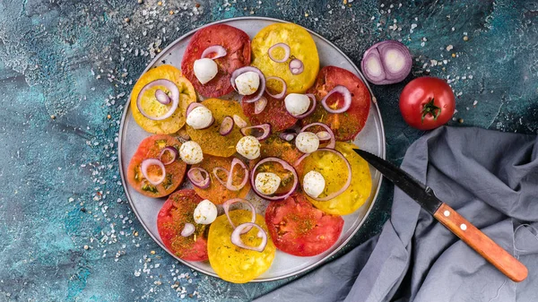 Food banner Tasty red and yellow tomatoes with onions, mozzarella cheese, salt and spices on a round plate