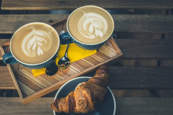 Two cappuccino and croissant on a table in a cafe