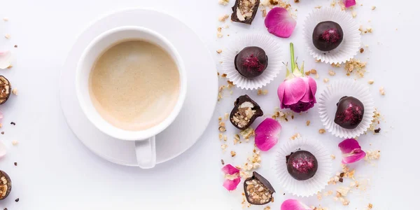 Food banner. White ceramic cup of coffee and chocolate candies with handmade nuts on a white background.