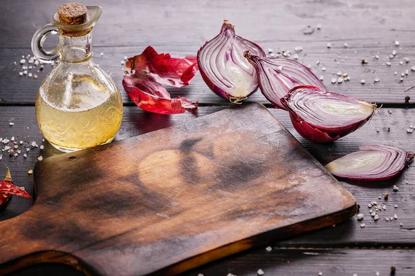 Wooden cutting board, red onions, hot peppers, spices and olive oil. Food still life