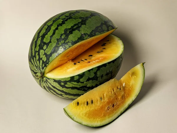 Ripe sweet yellow watermelon on a beige background. Organic and farm vegetables and fruits. Close up