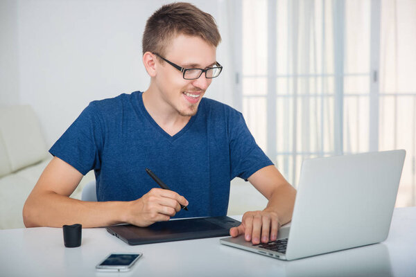 Man working with a graphics tablet behind a laptop