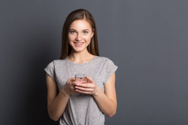 Gülümseyen gri arka plan üzerinde güzel genç kız