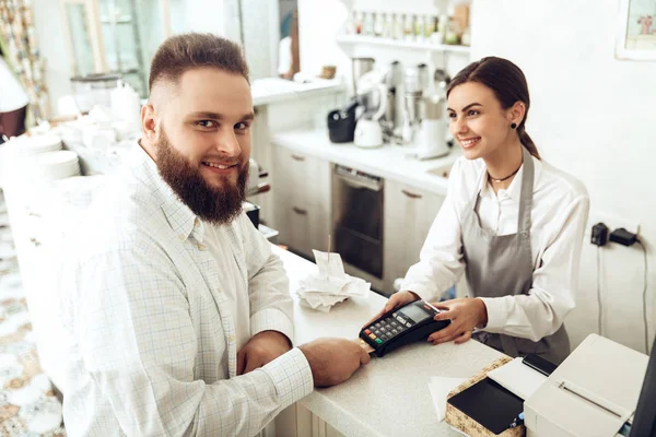 Cheerful cashier using digital device for payment