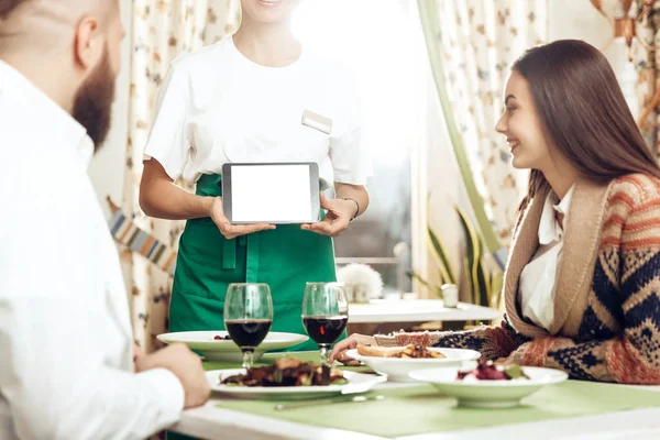 Girl waiter takes an order from a young couple