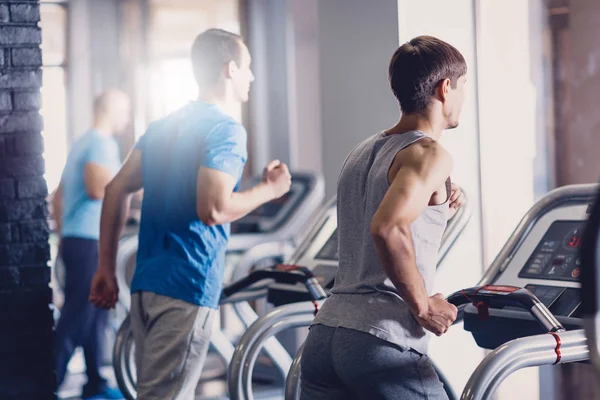 Un grupo de jóvenes haciendo footing en una cinta de correr . — Foto de Stock