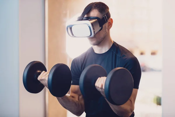 Man wearing virtual reality glasses with dumbbells