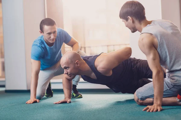 Trainer zeigt Richtigkeit von Liegestützen auf der einen Seite. — Stockfoto