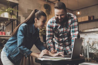 Kafede bir dizüstü bilgisayar üzerinde çalışan iki genç insan.