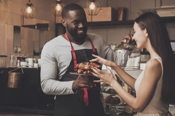 Αρσενικό barista βοηθάει μια κοπέλα για να επιλέξετε ένα επιδόρπιο — Φωτογραφία Αρχείου