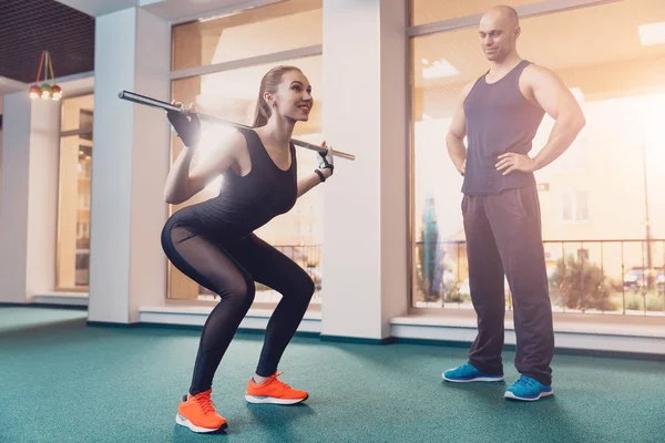 Chica haciendo sentadillas bajo el control de entrenador — Foto de Stock