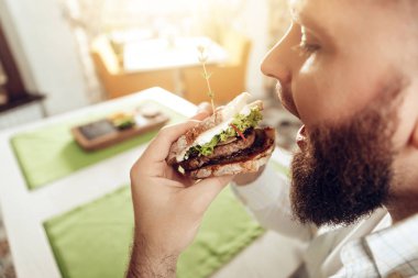 Arkadan görünüm adam ısırık sandviç kafede yemek