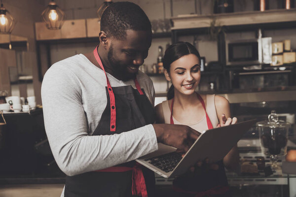 Barista man and woman looking at a laptop