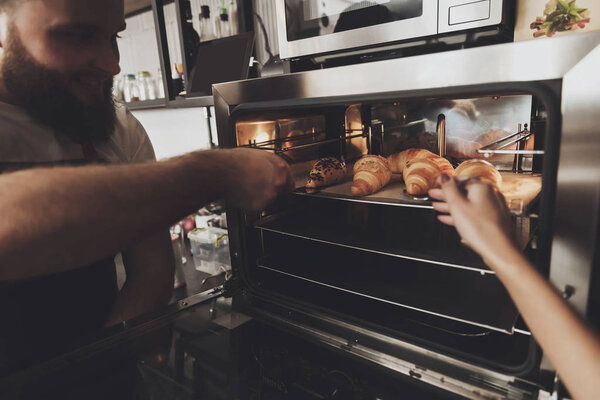 Два профессиональных пекаря стоят у печи
.