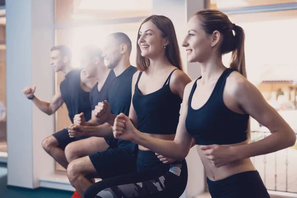 Grupo de hombres y mujeres realiza un ejercicio físico . — Foto de Stock