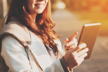 Gülümseyen kız güneşli park sokakta tablet kullanma.