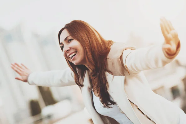 Smiling girl running with hands in air outdoors.