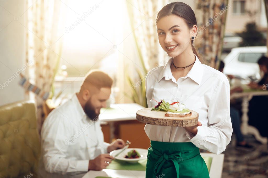 Portrait young waitress holding sandwich on plate