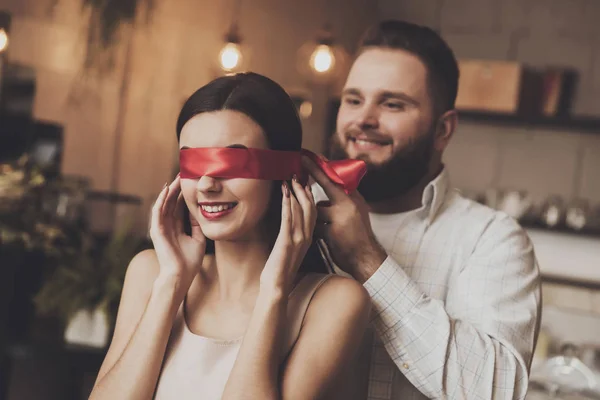 Um homem está amarrando uma linda garota com uma fita vermelha — Fotografia de Stock