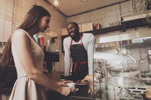 Smiling barista man gives a girl her order