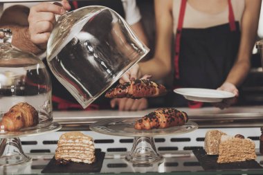 Genç bir kız çörek dükkanı penceresinden alır.