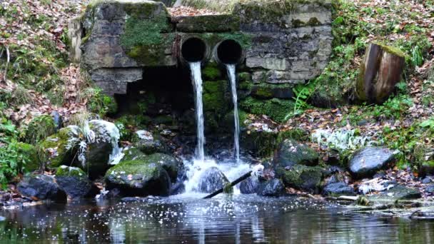 From the pipes flowing water coming from the depths of stone rocks — Stock Video