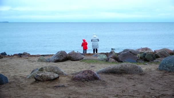 Mère et fille jettent des pierres dans l'eau du front de mer — Video