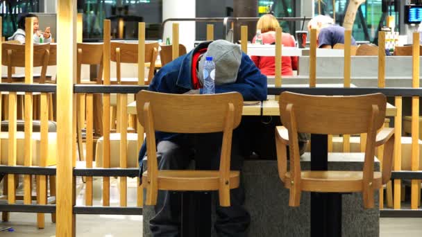 Hombre durmiendo en una mesa en una cafetería del aeropuerto — Vídeos de Stock