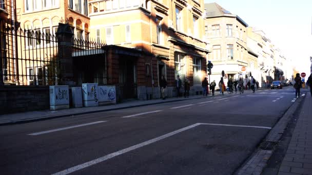 Ciclistas cabalgan en la calle con peatones en la acera — Vídeo de stock