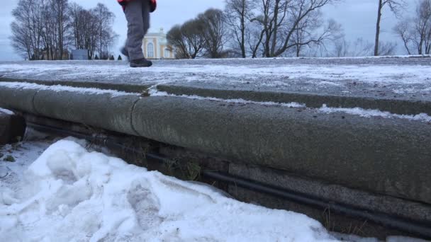 Barnens fötter gå på snötäckta piren i parken — Stockvideo